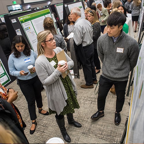 Student presenting poster research to crowd at UAB Expo event.