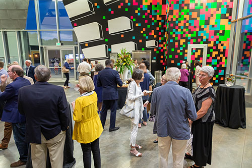 Groups of people standing around and talking in AEIVA gallery.