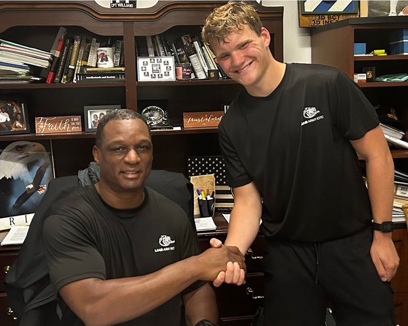A 4-year scholar shakes hands with his commander.