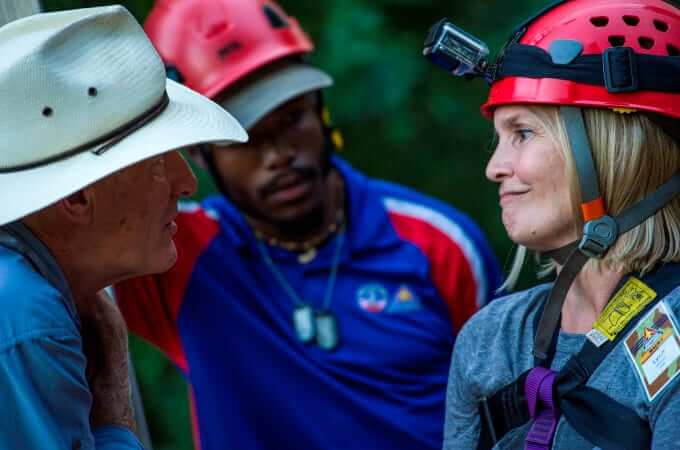 Two students in helmets and a program leader gathered together.