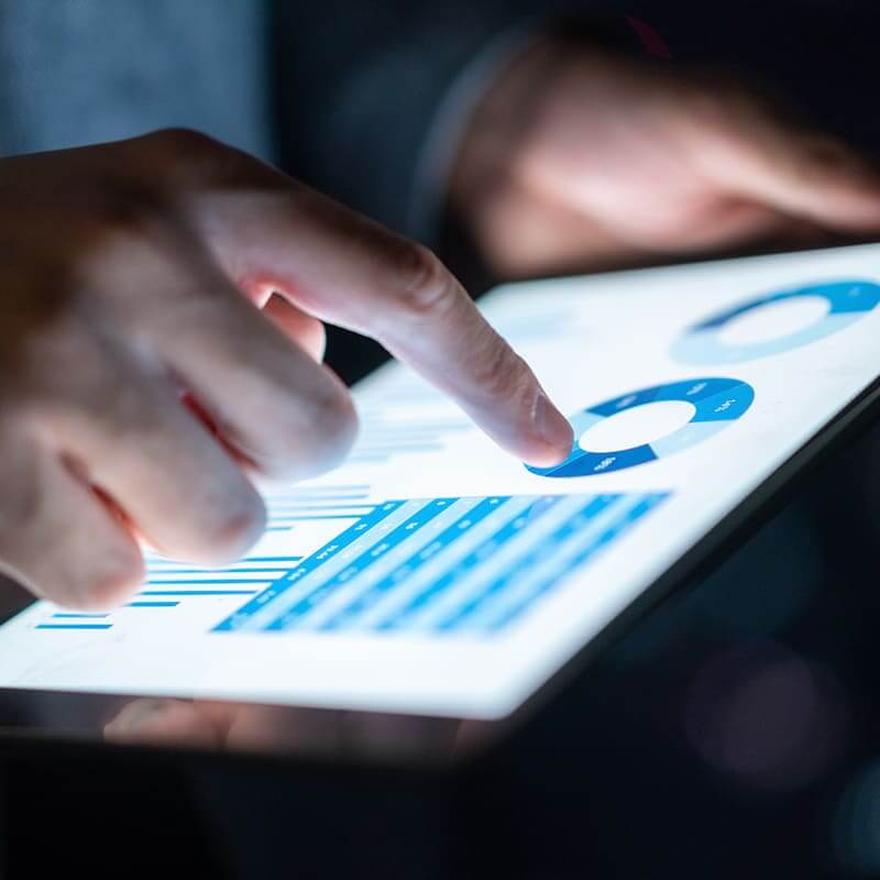 Close up of hands holding a tablet that is displaying circle graphs.