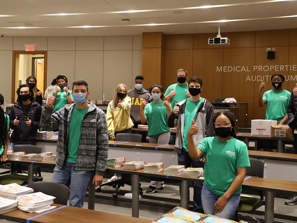 Collat Scholars packing supplies and giving thumbs-up signs. .