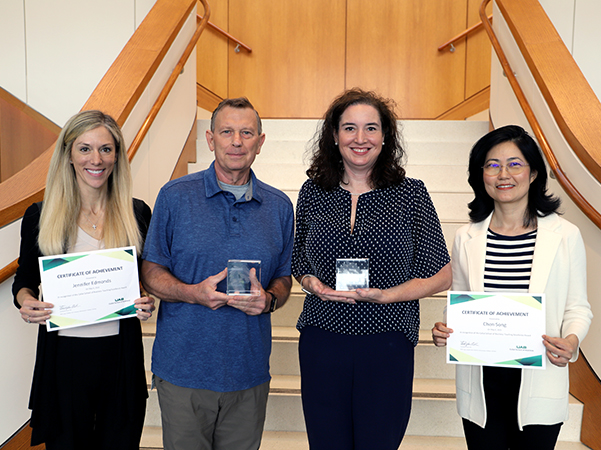 Four business faculty members holding awards