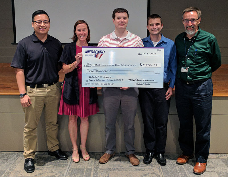 Students holding an oversized check representing a donation received to the fund.