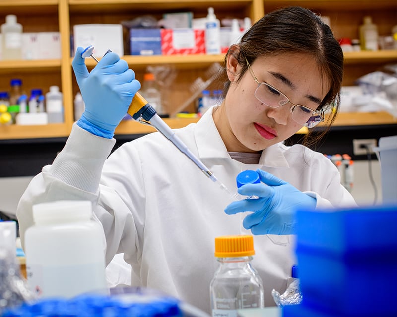 Student pipettes in a research lab