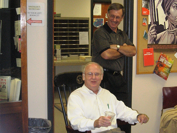 Dr. Carl McFarland (standing) with Dr. Tennant McWilliams (seated) at a reception. Photo courtesy of Dr. McFarland.