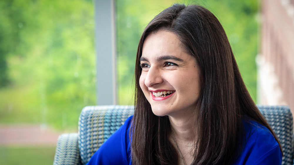 Tehreem Khan smiling in a bright blue shirt, looking to her left. 