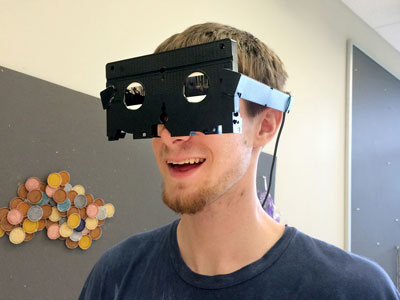 A student looking through a viewfinder maid from a VHS cassette.