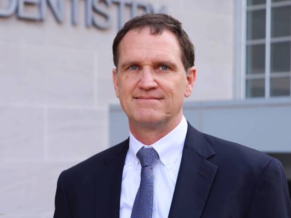 Dr. Bowie in professional attire standing in front of UAB School of Dentistry