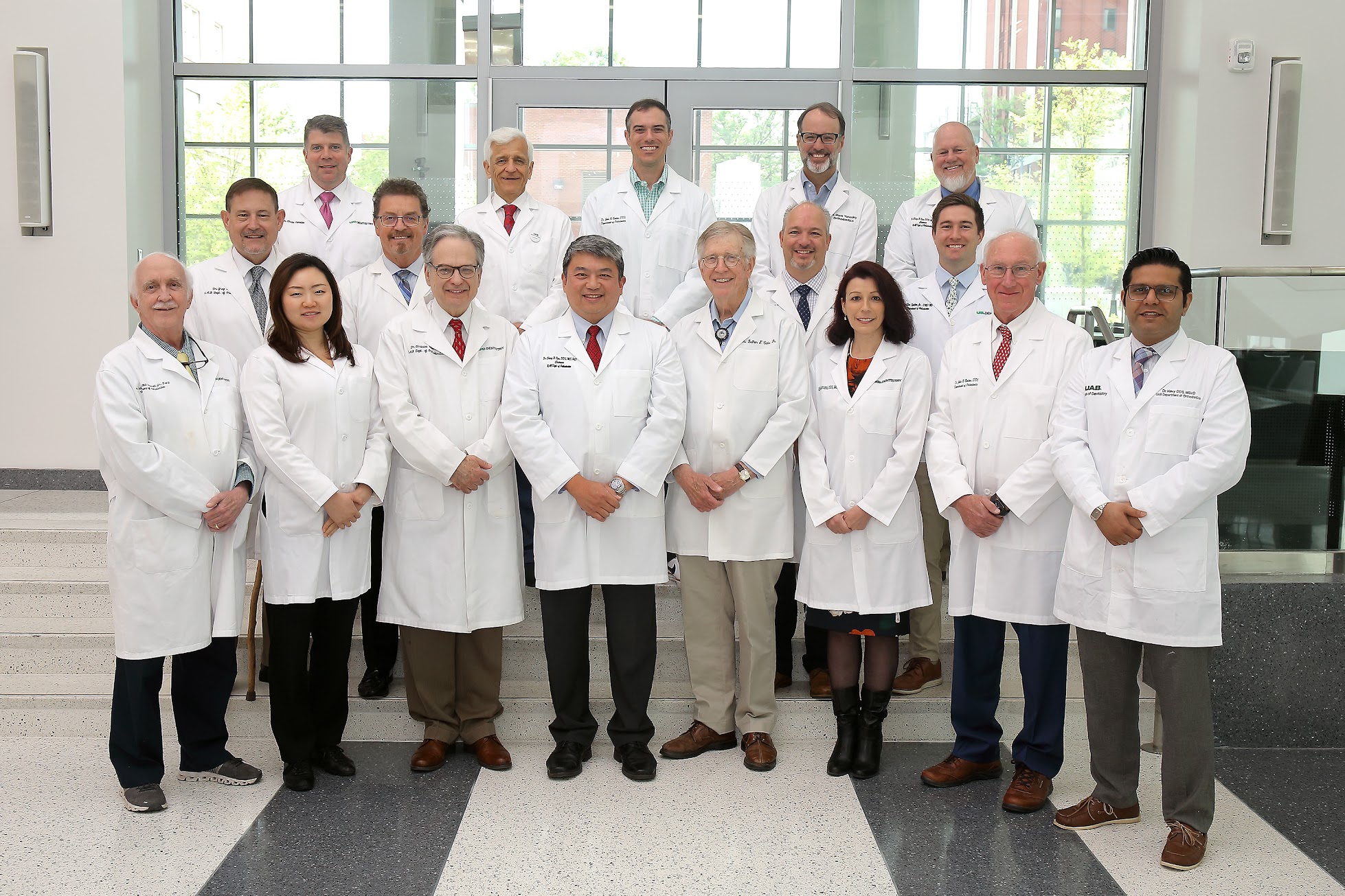 Group photo of UAB Orthodontics faculty in white coats in a conference center