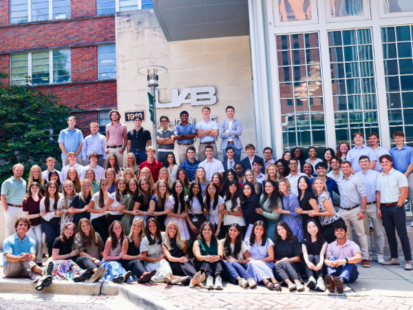Large group of first-year dental students posing for class photo in front of the school