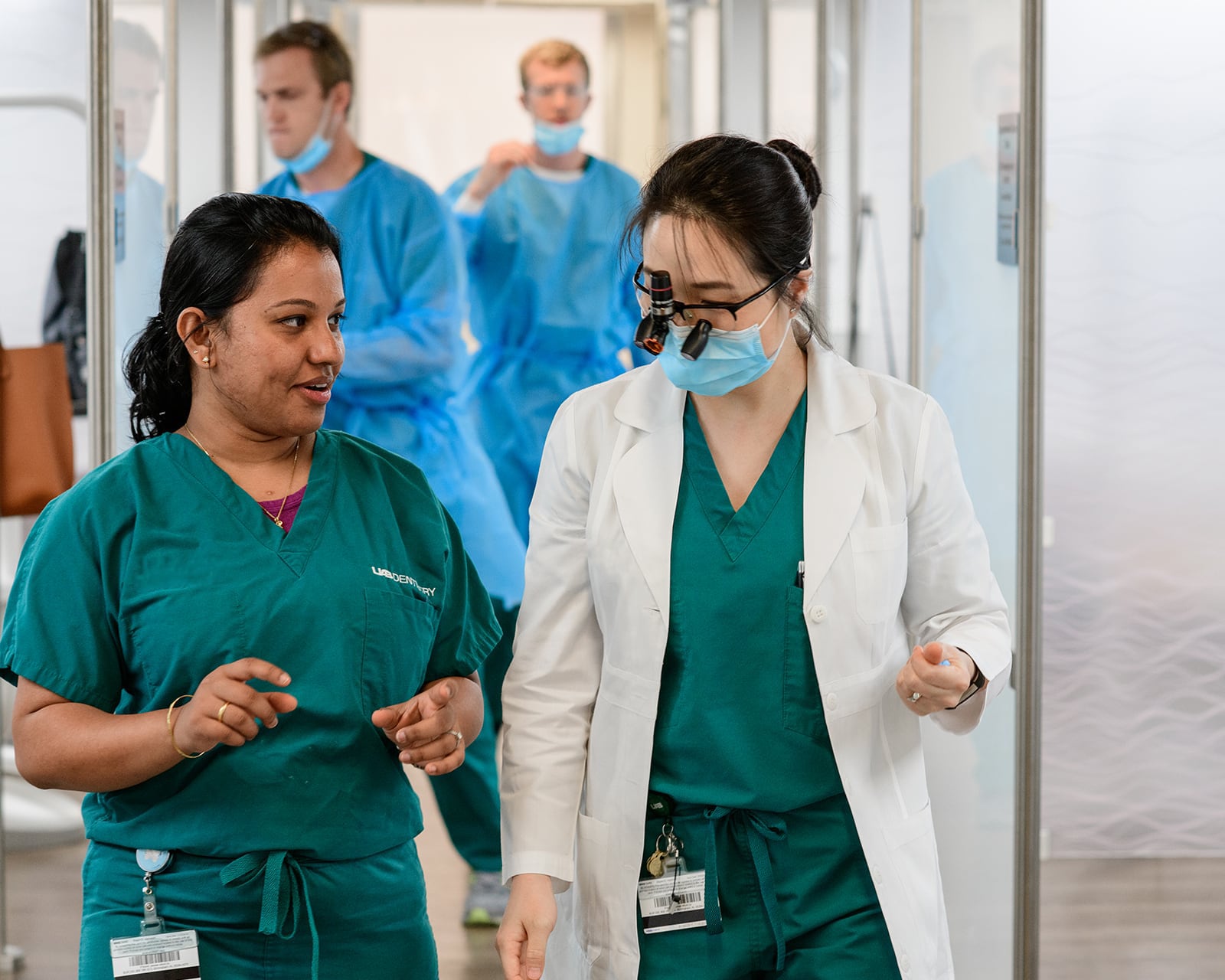Two dentists talking while walking through a clinic hallway.