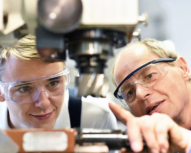 Student and professor examining equipment in lab.