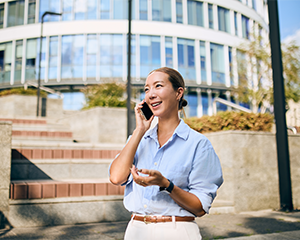 Woman talks on a cellphone while walking down a city street
