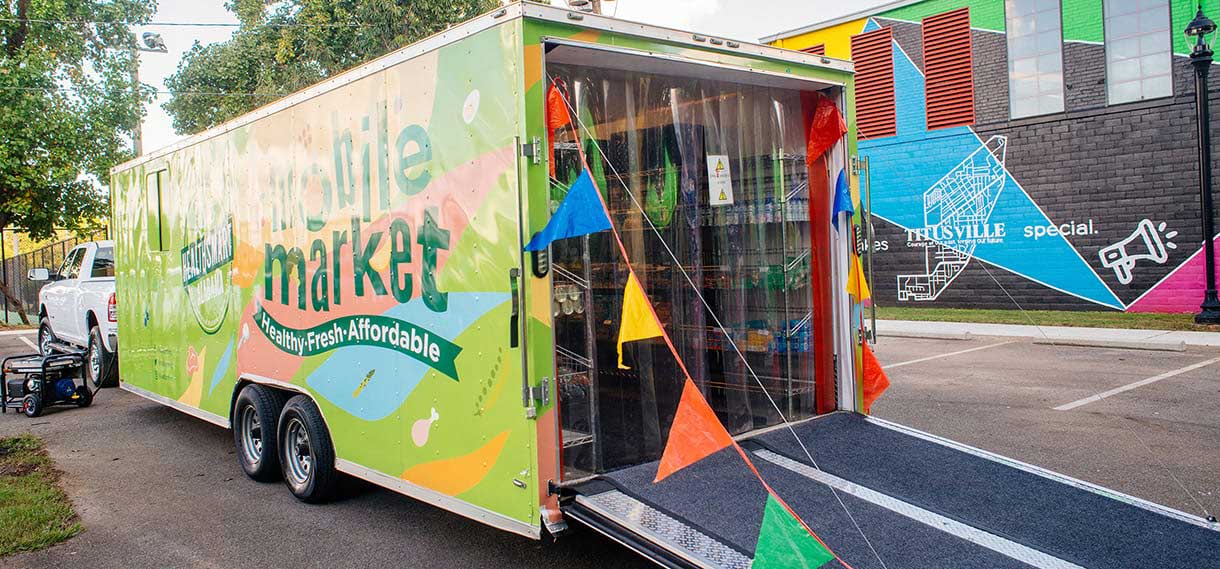 Mobile market trailer, open with colorful banners.