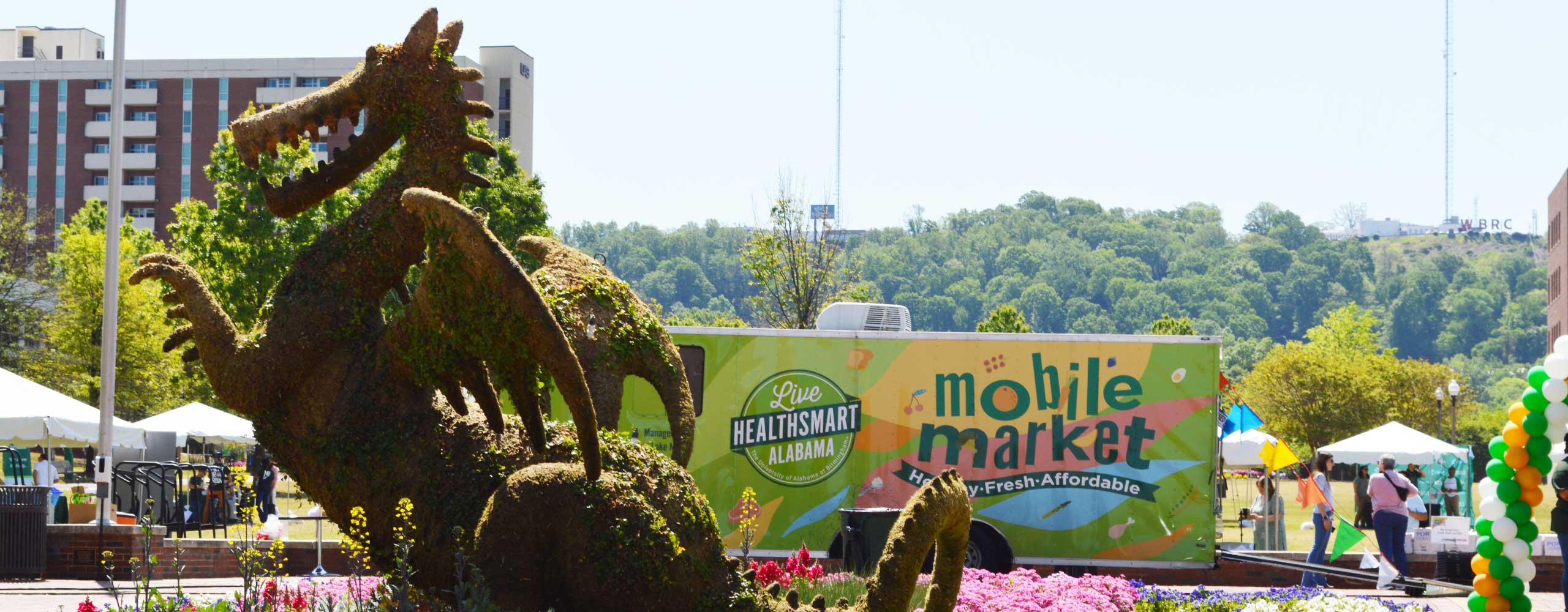 The Live Healthsmart mobile market van, with a dragon topiary in the foreground. 