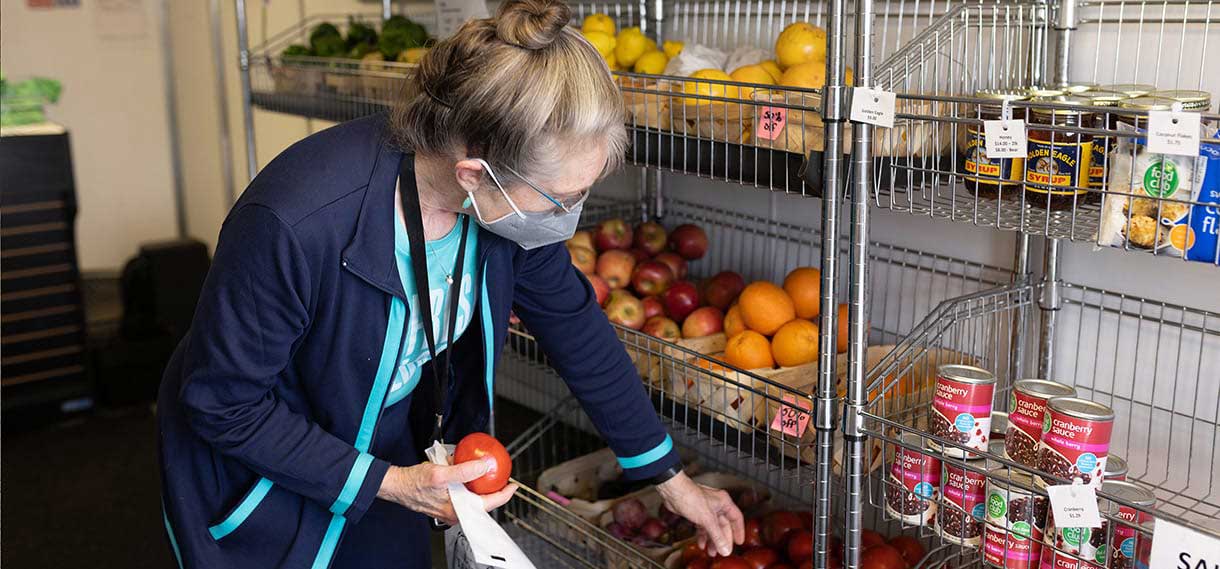 A blonde white woman picks out food in the mobile market.