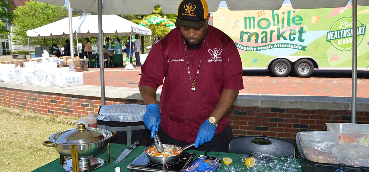 A Black male chef at an outdoor cooking demonstration.