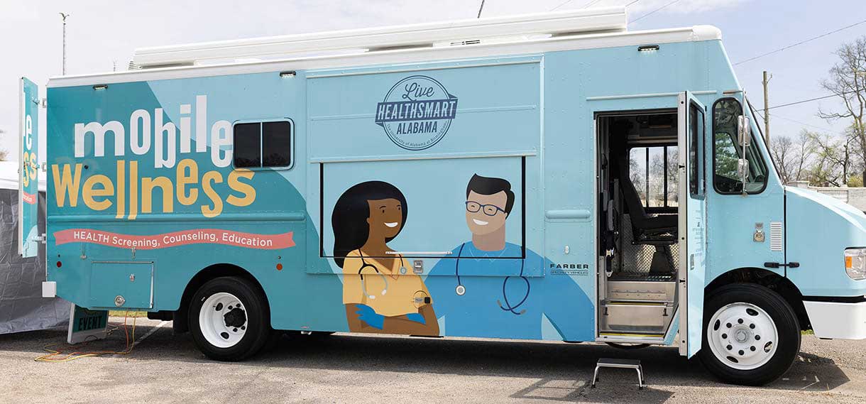 The blue and teal van, with illustrations of two health workers on its side.