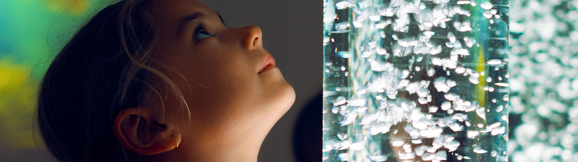 A child gazes into a mesmerizing bubble lamp- a common tool for calming overstimulated children with autism spectrum disorders.