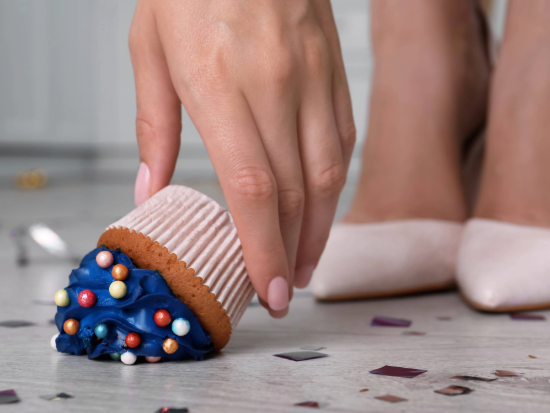 Image of someone picking up a dropped cupcake on the floor