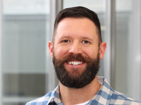 Drew Sayer, Ph.D., smiles in front of a window