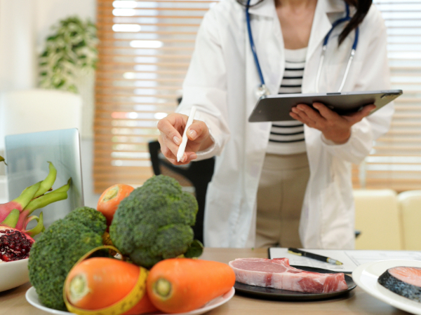 Doctor in white coat points to vegetables