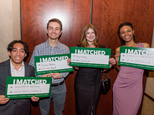 Group of four students standing together holding I Matched signs