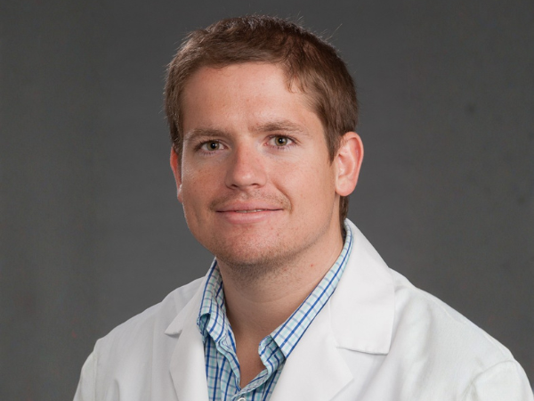 Man wearing white doctor coat against dark background 