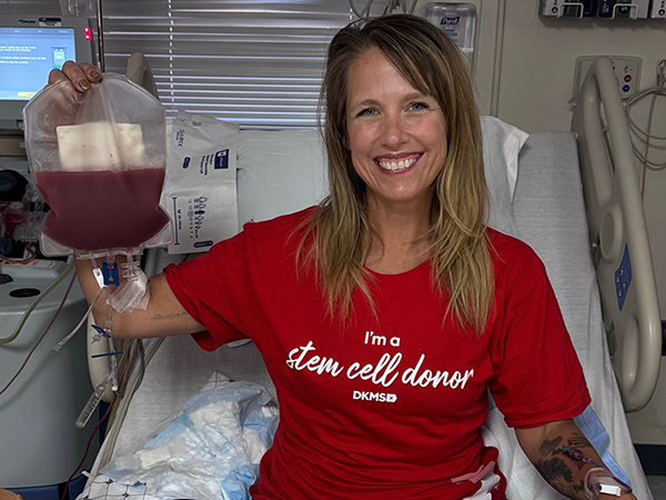 Jenn Coker, PhD sitting in a hospital bed donating blood for a research study