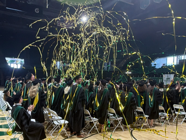 Medical students celebrate together as green and gold streamers fall around them at the end of Commencement 2026.