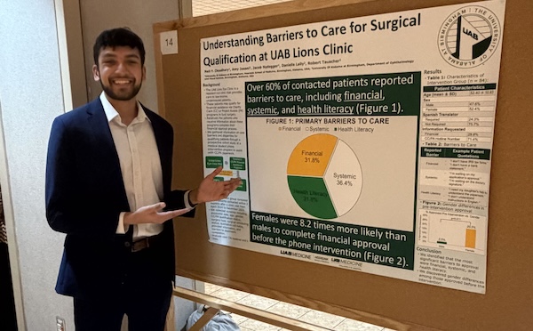 Poster presenter poses in front of poster.