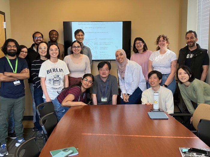 Photo of Shin-ichi Kano, M.D., Ph.D., and his research team in a conference room.