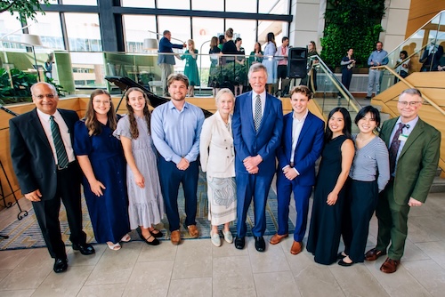 Dr. Heersink stands with Dr. Agarwal, Dr. Van Wagoner, and medical student performers in front of grand piano.