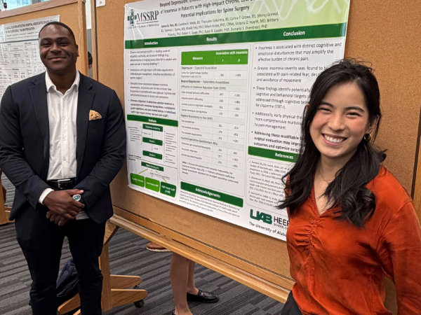 Poster presenters pose in front of poster.
