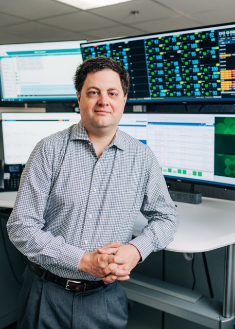 UAB Hospital-Highlands. Dr. Michael Lyerly, MD (Associate Professor, Neurology) is standing in front of a large cube with a network of teleheath (telemedicine) monitors that monitor telestroke (teleneurology) patients, May 2024.