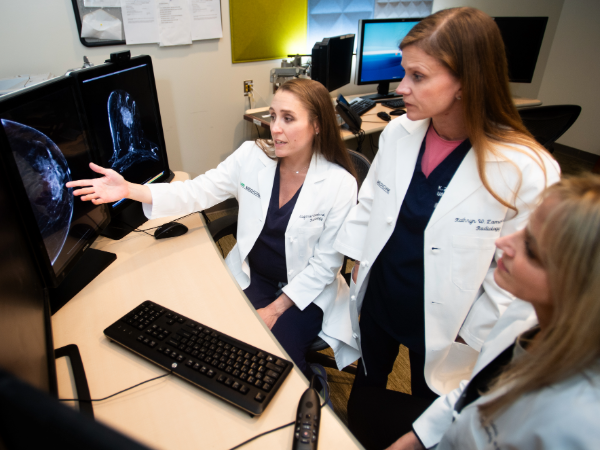 Three breast faculty physicians reviewing imaging on a computer