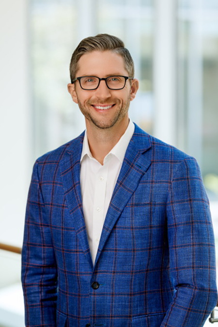 Headshot of Kenny Shafer in a blue, patterned blazer with a white button up shirt. 