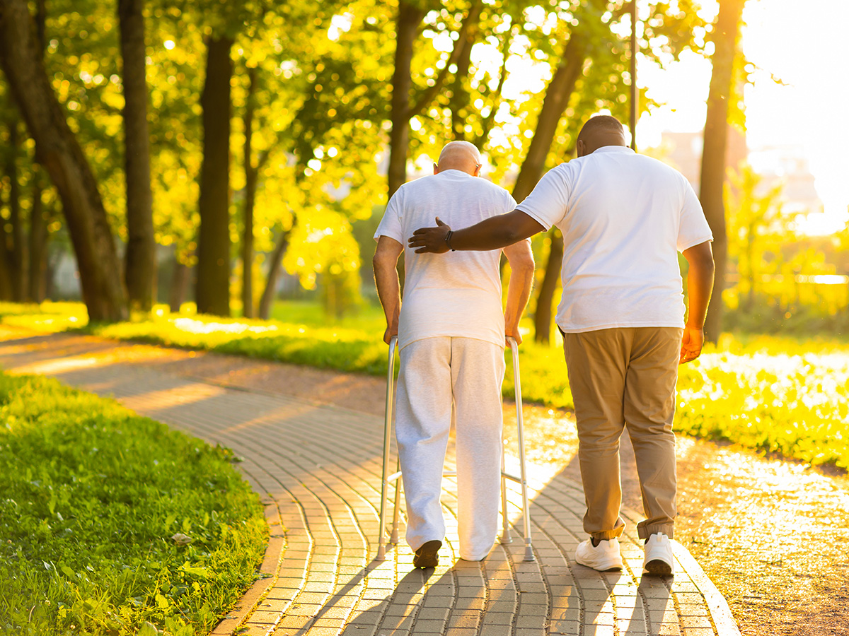 An black man helping a white man with a walker