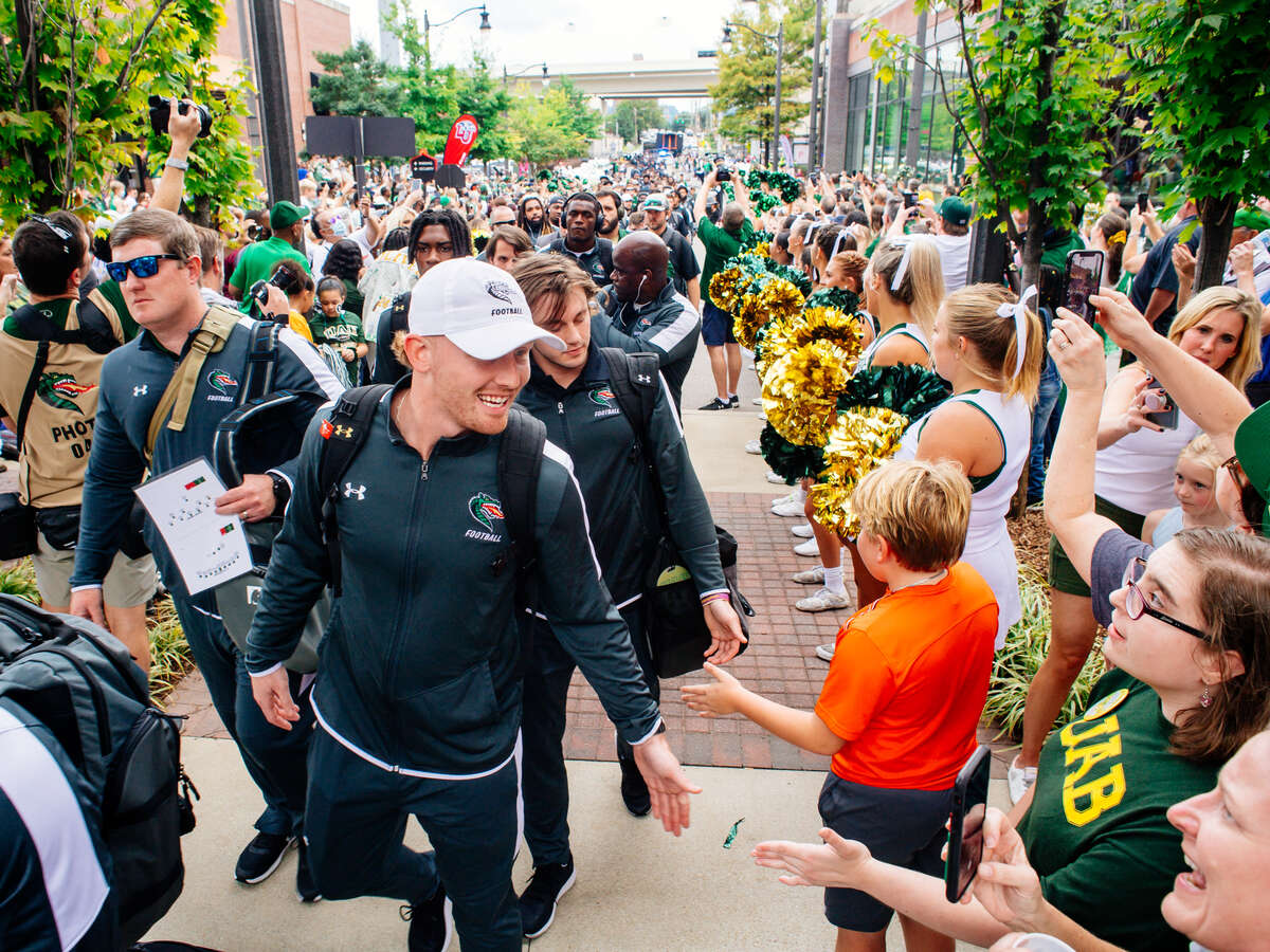 UAB football players are walking between fans while going into the stadium prior to the game.