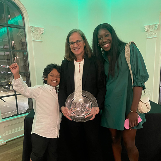 Two women and a child posing with an award