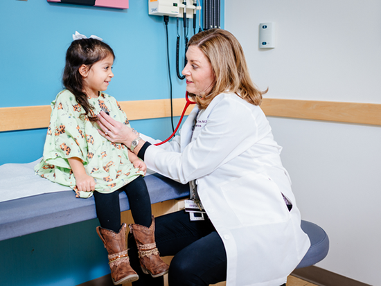 Female doctor using stethoscope on female child.