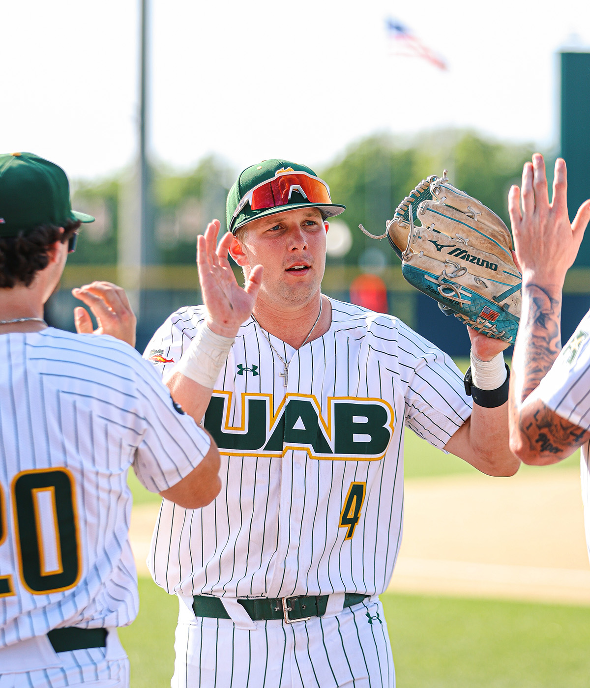 Tyler Waugh wearing his UAB baseball jersey giving his teammates a high five.