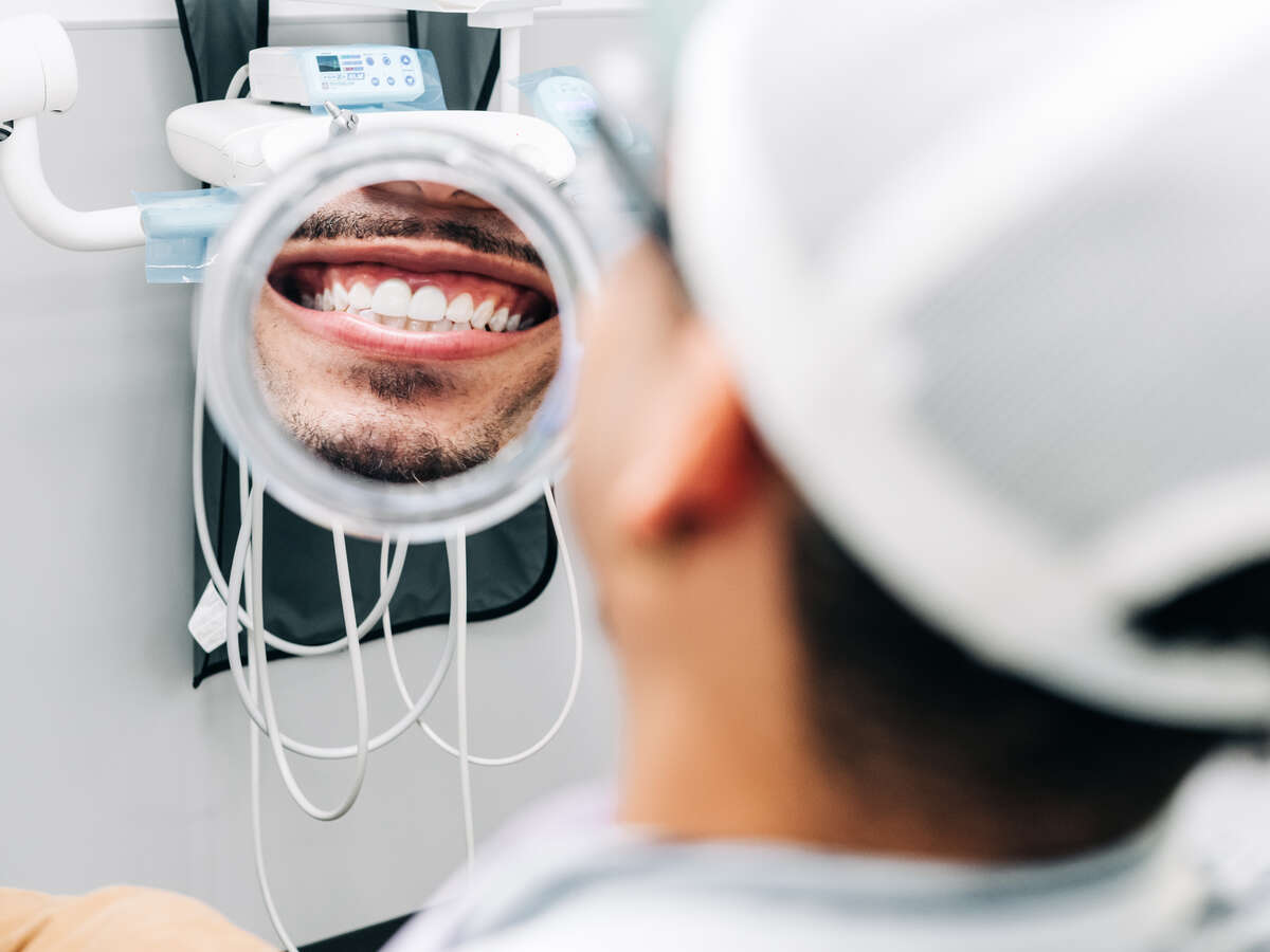 Photo of a man smiling and looking at his teeth in the UAB Dentistry Clinic.