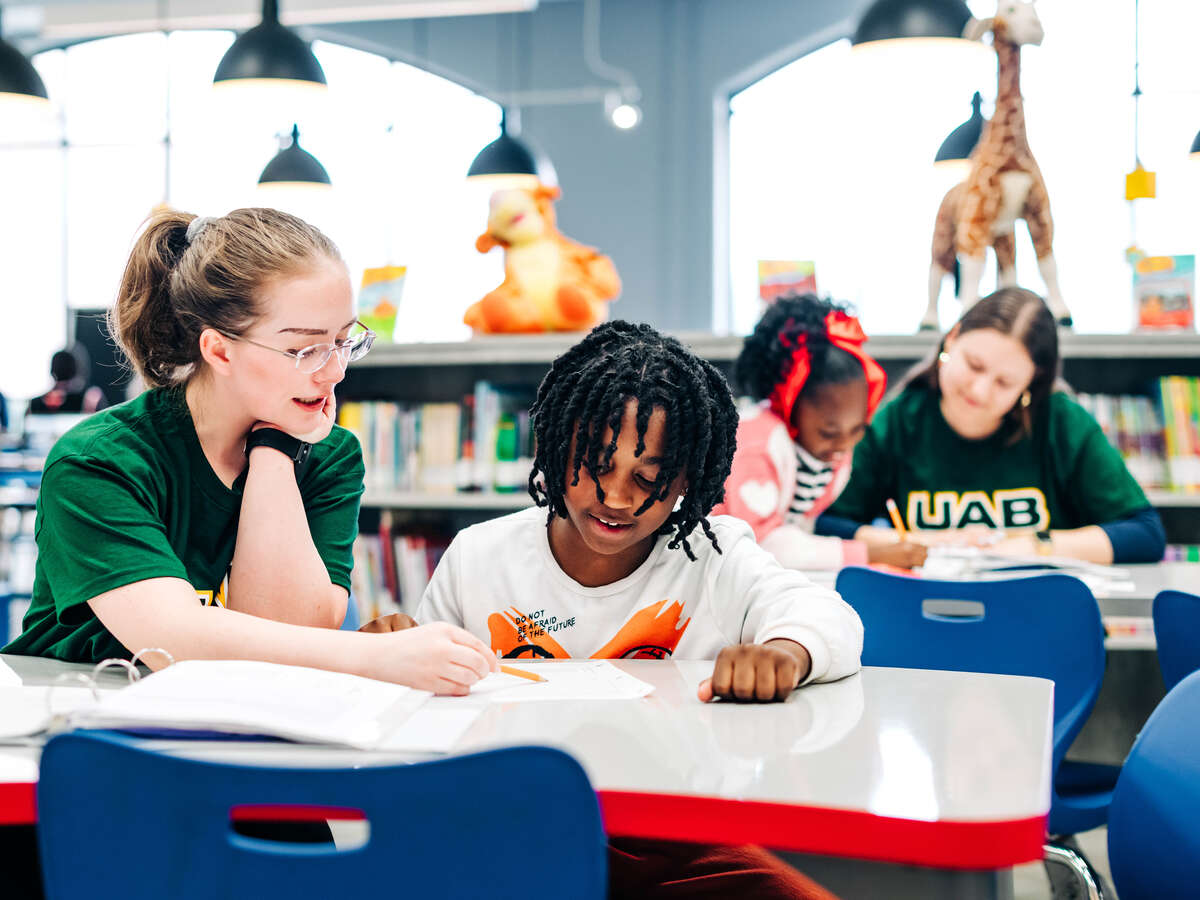 Two UAB student volunteers are tutoring second-grade students in reading skills.