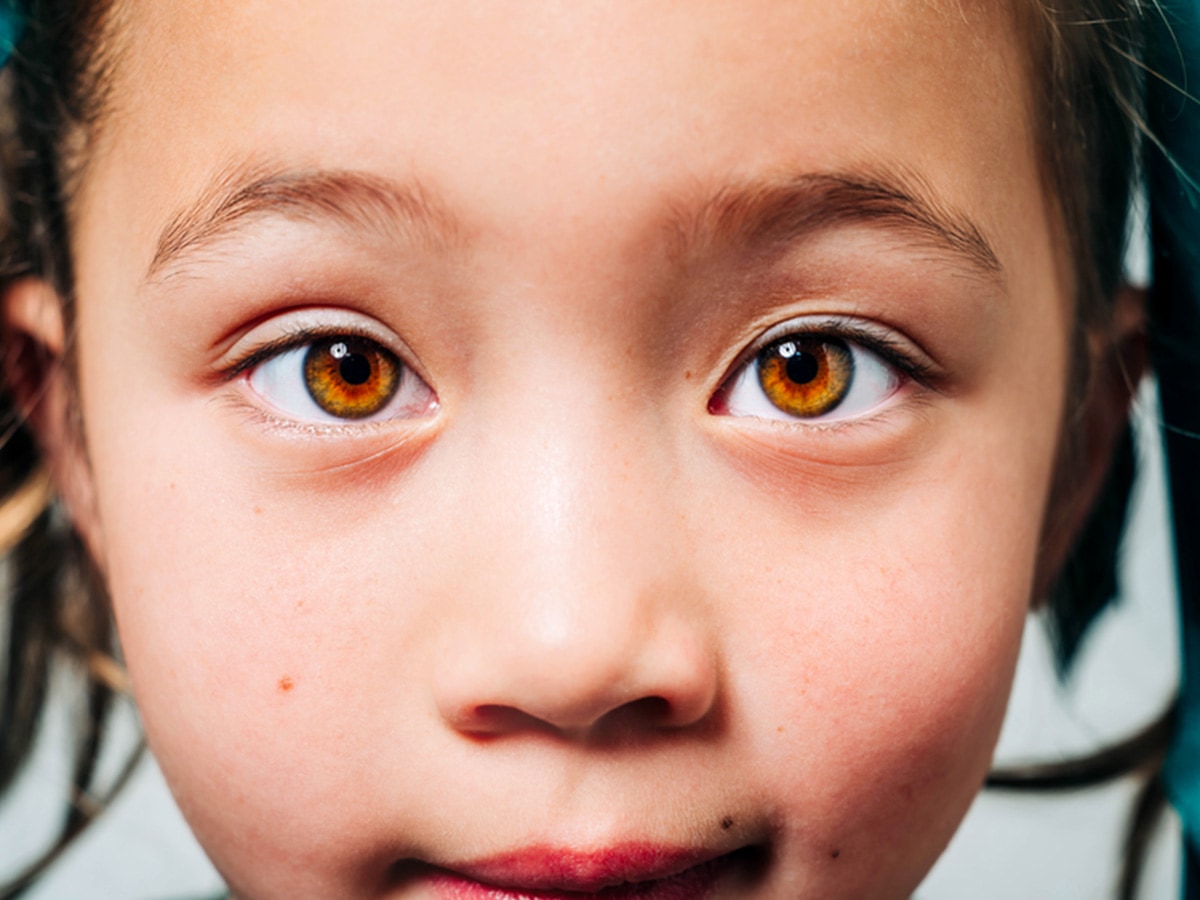 Close up photo of young Asian girl looking straight into the camera, emphasizing her light brown eyes.