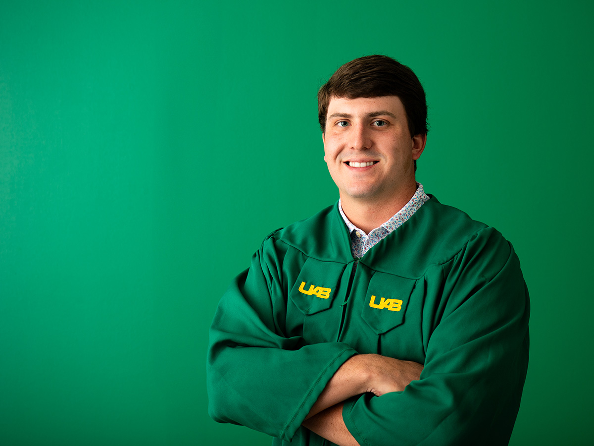 Charlie Goode's headhsot wearing the UAB graduation gown against a green background