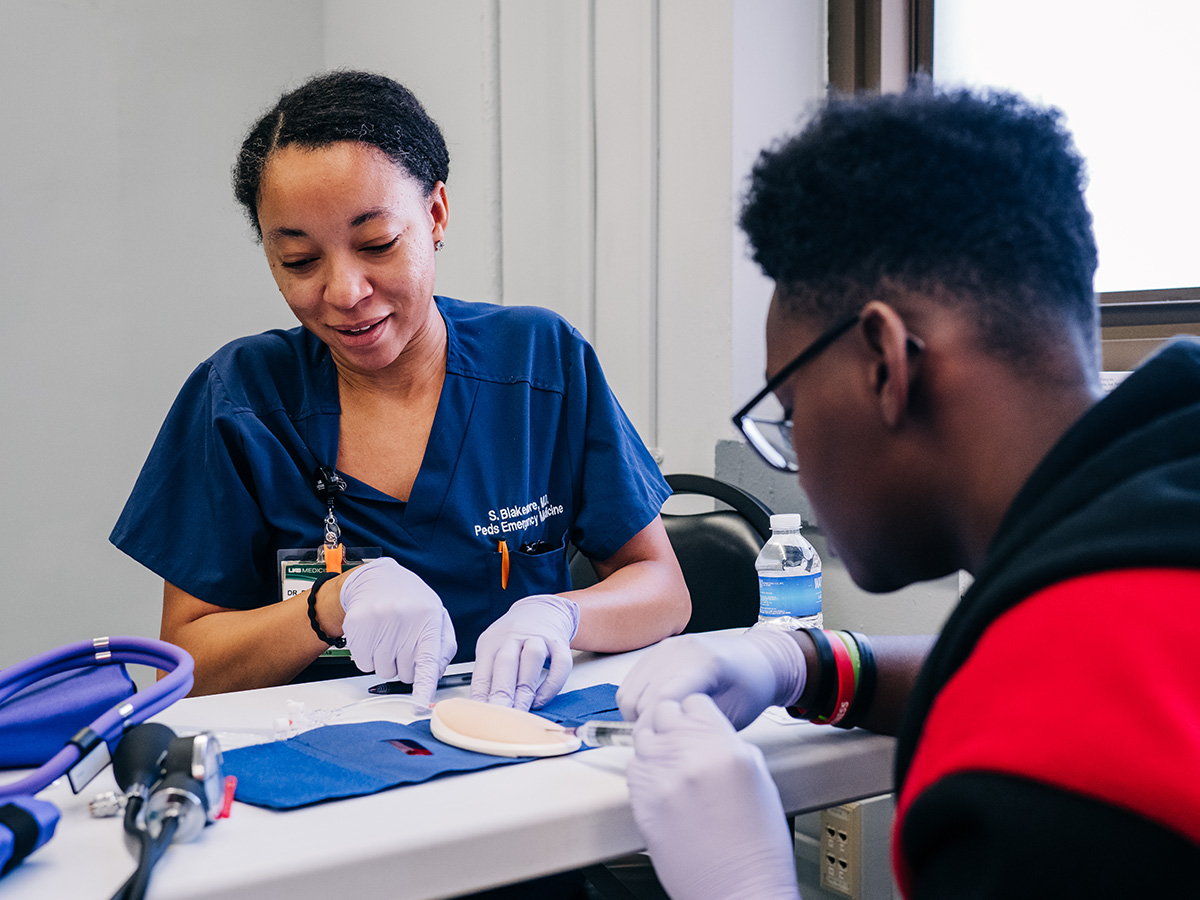 Dr. Shaundra Blakemore teaching a young medical student at a desk for UAB's Mini Med School.