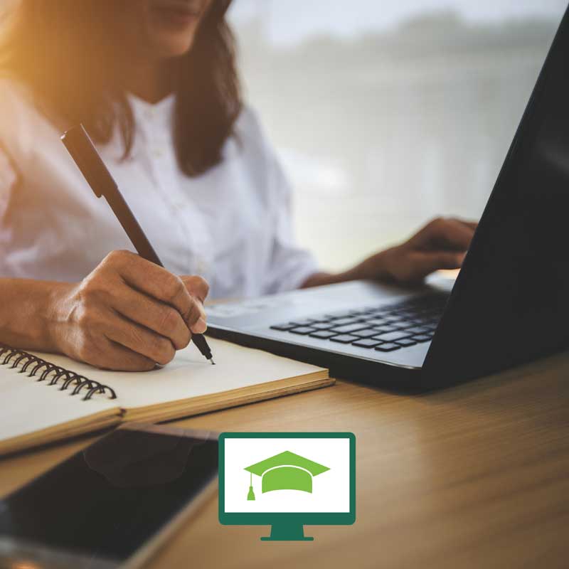 Three female students sitting around a small table with binders and a laptop, in front of a window.