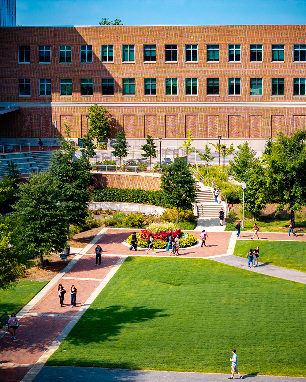 Students walk across the campus green in between classes with University Hall in the background